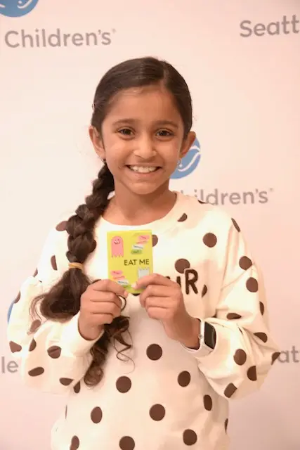 Maya proudly holding up the EAT ME card